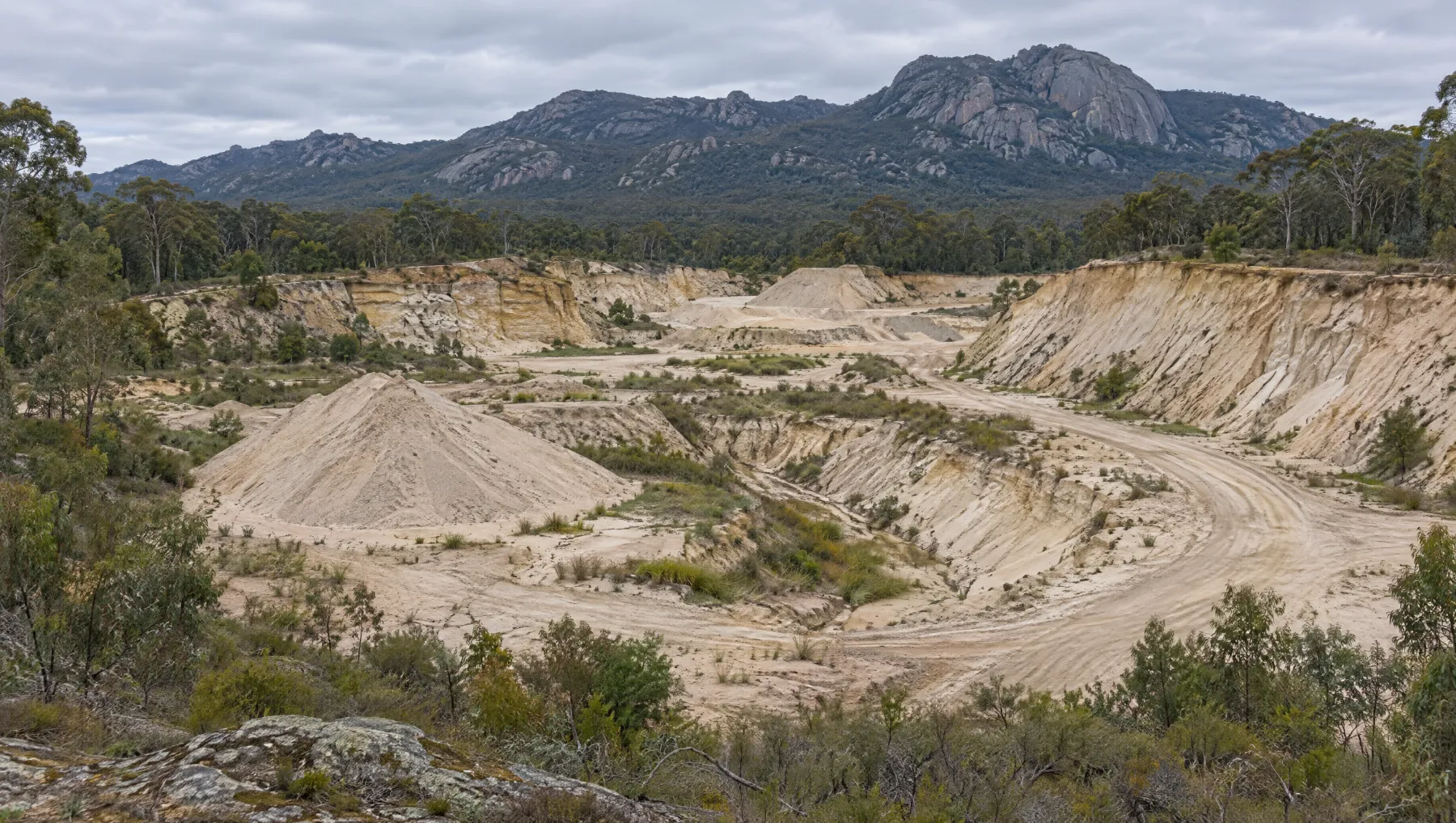 Illustration of a disused sand quarry at the foot of a granite range